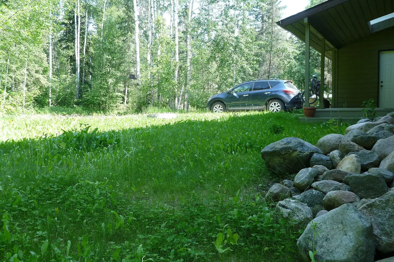 Cabin yard with car and boulders in the boreal forest, 2013