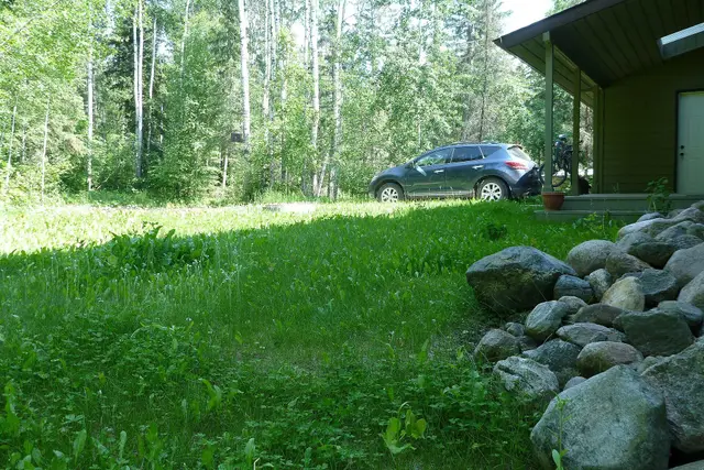 Cabin yard with car and boulders in the boreal forest